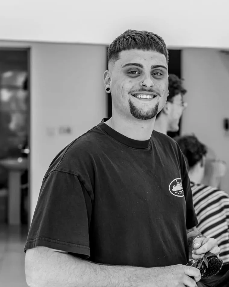 Beppe, owner of Mus Cuts, smiling in the shop with clippers in hand